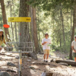 Three disc golf players tackle the forests of the Lost Lake course in Whistler.