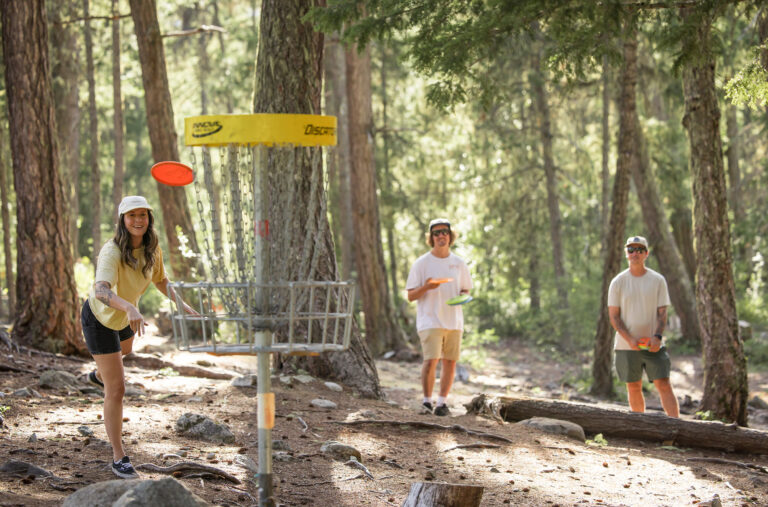 Three disc golf players tackle the forests of the Lost Lake course in Whistler.