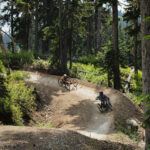 Two adaptive mountain bike riders make their way down the berms of the Whistler Mountain Bike Park.