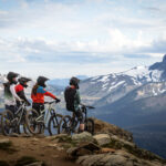 A group of mountain bike riders enjoy the view of Black Tusk from the Top of the World Trail on Whistler Mountain.