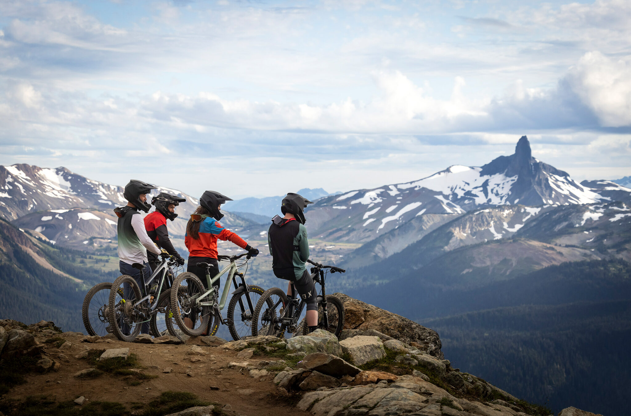 A group of mountain bike riders enjoy the view of Black Tusk from the Top of the World Trail on Whistler Mountain.