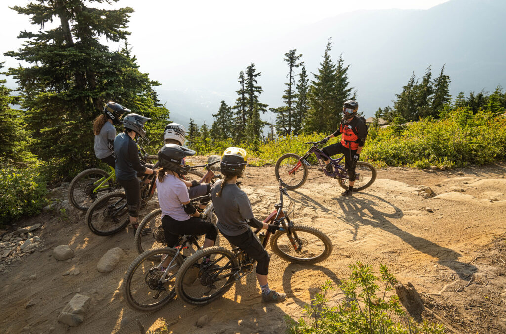 A group of mountain bikers listen to their instructor on a lesson in the Whistler Mountain Bike Park.