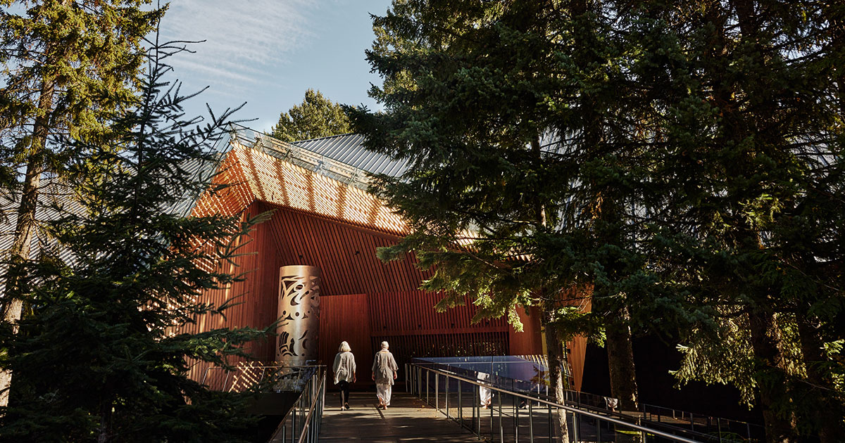 The Audain Art Museum as seen from the outside, main entrance in the sunshine with two people walking up the walkway.