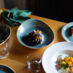 A selection of colourful, fall food dishes laid out on a wooden table at The Den at Nita Lake Lodge, Whistler.