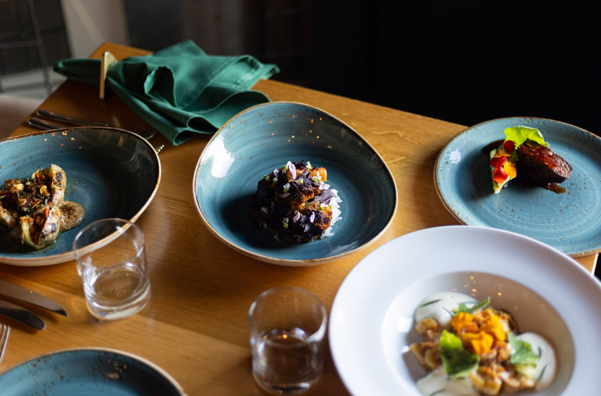 A selection of colourful, fall food dishes laid out on a wooden table at The Den at Nita Lake Lodge, Whistler.