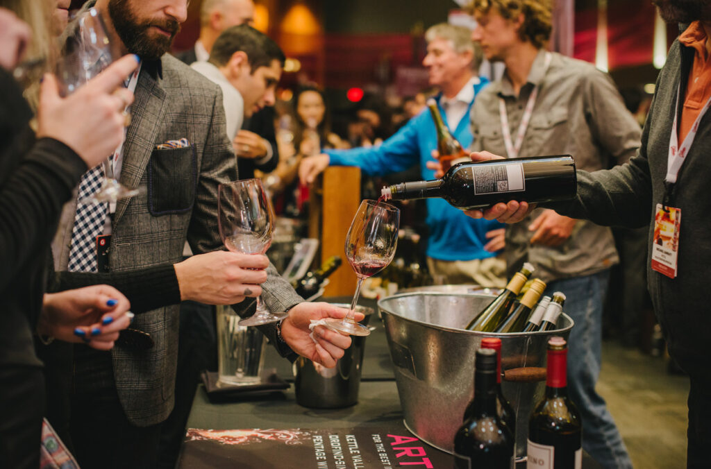 Guests hold out their wine glasses to get a tasting of what's on offer.