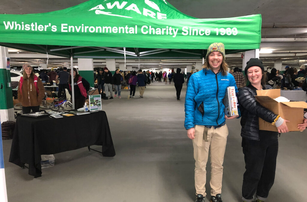 Two people happily take away a box of goodies from AWARE's community garage sale.