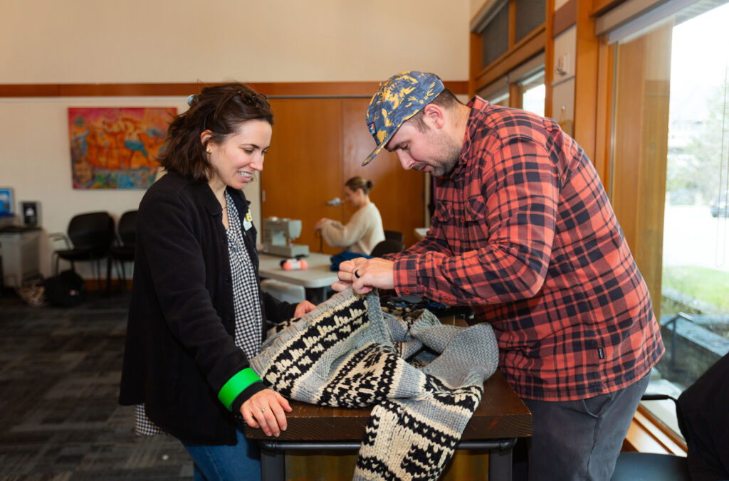 Two people look at a sweater at AWARE's repair cafe at the Whistler Public Library.