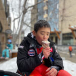 A young person enjoys a Rocky Mountain Chocolate Shop ice cream in the snow.