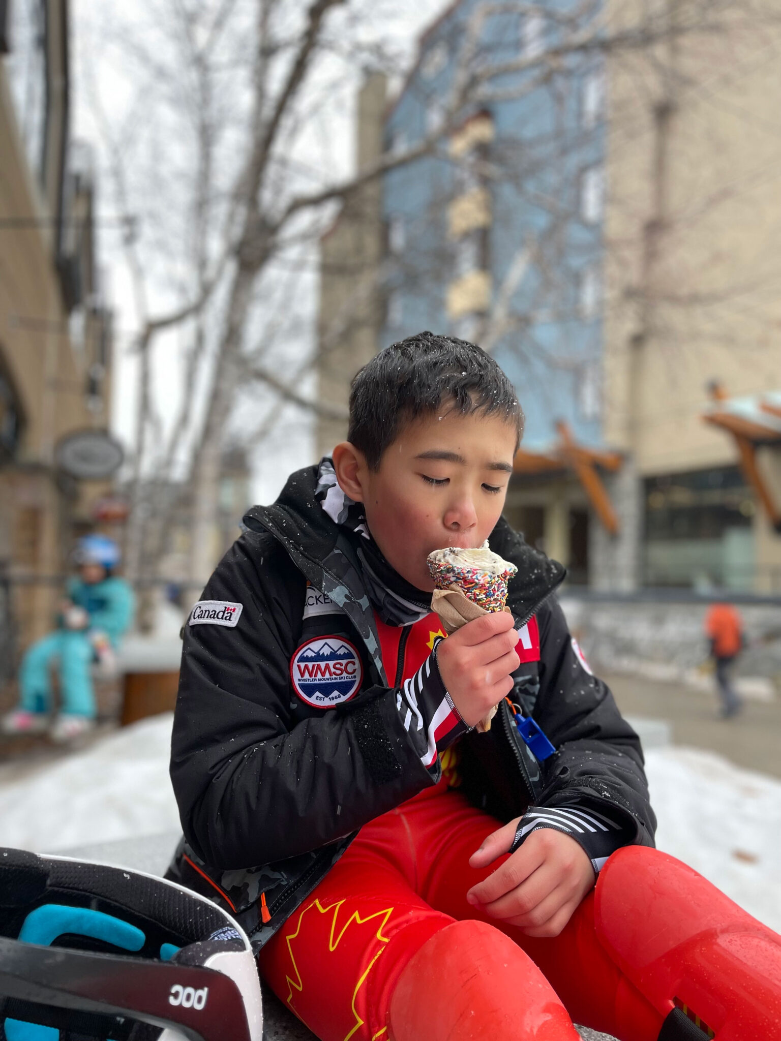 A young person enjoys a Rocky Mountain Chocolate Shop ice cream in the snow.