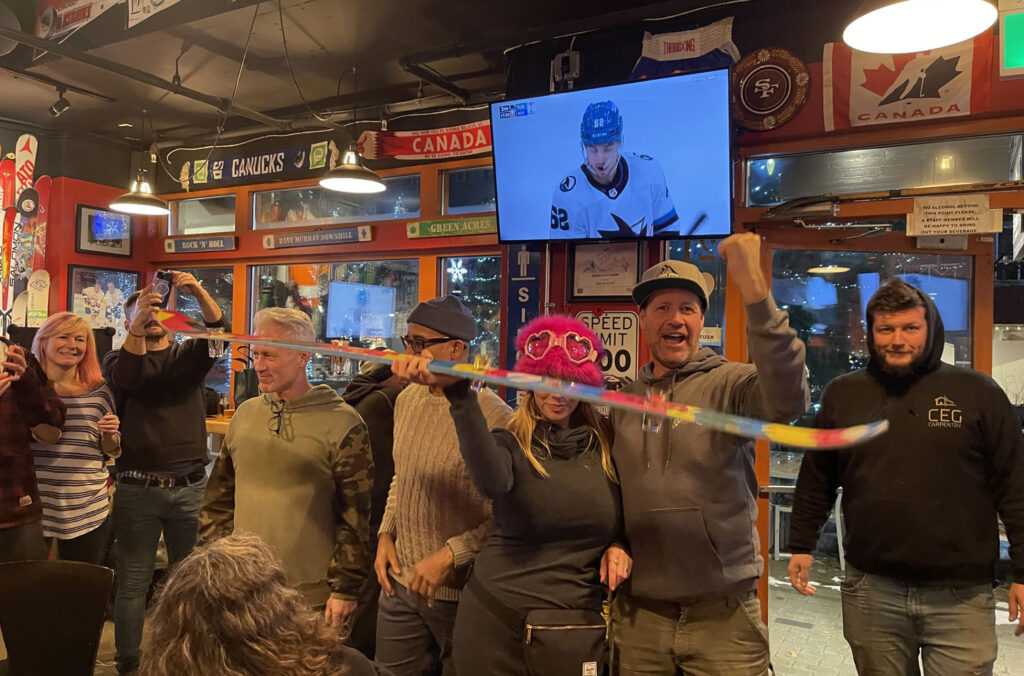 A group of people stand in Stinky's in Whistler and raise a shot ski.