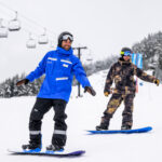 A snowboard instructor teaches an adult how to snowboard on Whistler Blackcomb.