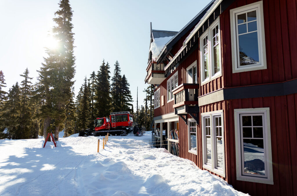 A red snowcat sits outside the Journeyman Lodge in the snowy backcountry of the Callaghan Valley, Whistler.