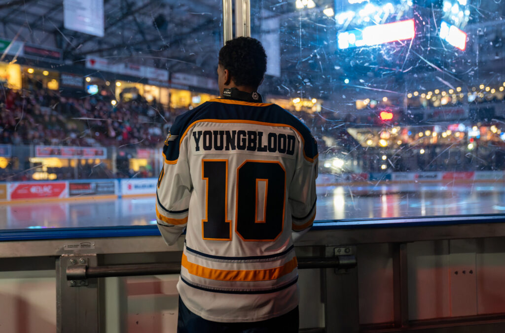 A hockey player looks out over a crowded ice rink wearing a jersey that says 'Youngblood".