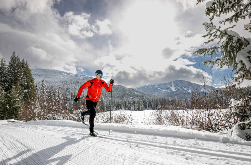 A person in a red jacket cross-country skis at Lost Lake Park in Whistler.