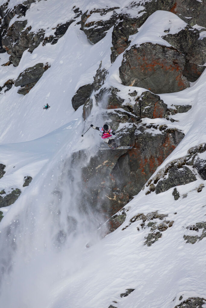 Freeride ski athlete WeiTien jumps off a cliff during a line at the Freeride World Tour comp 2023/24.