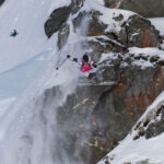 Freeride ski athlete WeiTien jumps off a cliff during a line at the Freeride World Tour comp 2023/24.