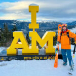 Combat diver, Alin Mirea stands in front of the I AM Invcitus Games sign on Whistler Mountain in his ski gear.