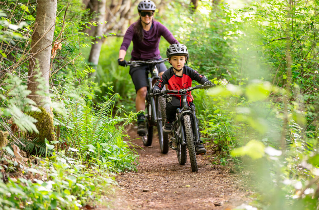 Sara Nibok bike rides with her son in Whistler on a dirt trail.