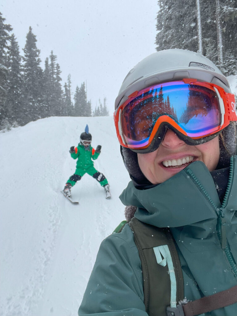 Nina skiing on Whistler Blackcomb with her son who's skiing behind her on a snowy day.