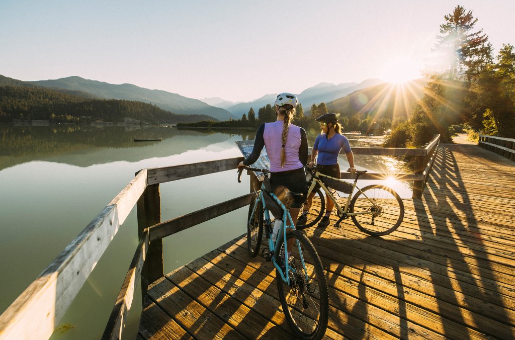 Two bike riders take a break looking out over Green Lake in Whistler in the spring.