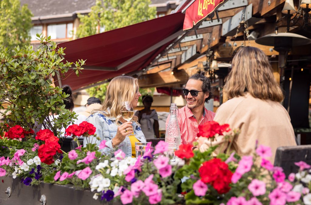 A group of friends dine and drink on a sunny patio in Whistler.