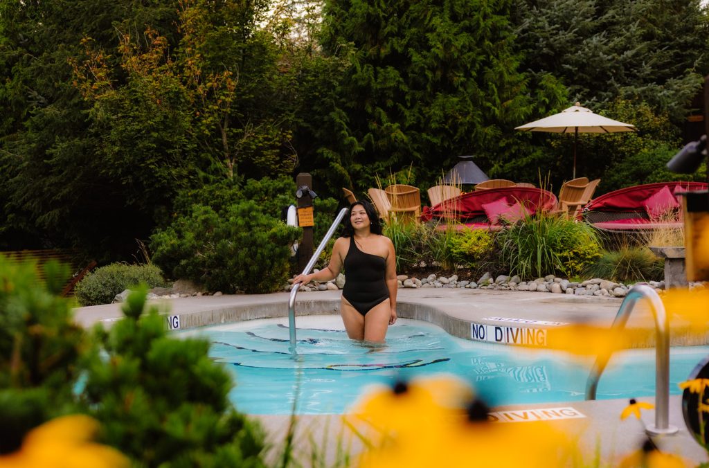 A person enters a pool at the Scandinave Spa in Whistler. Flowers line the pathways.