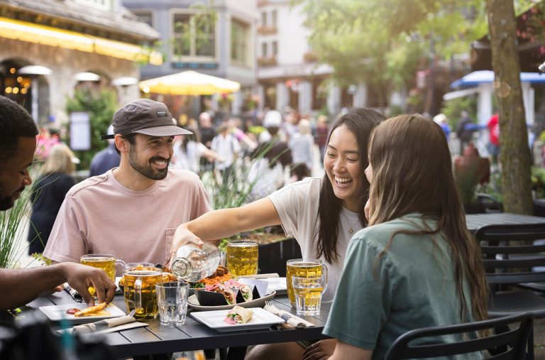 Three friends eat on the patio of The Beacon on Whistler's Village stroll.