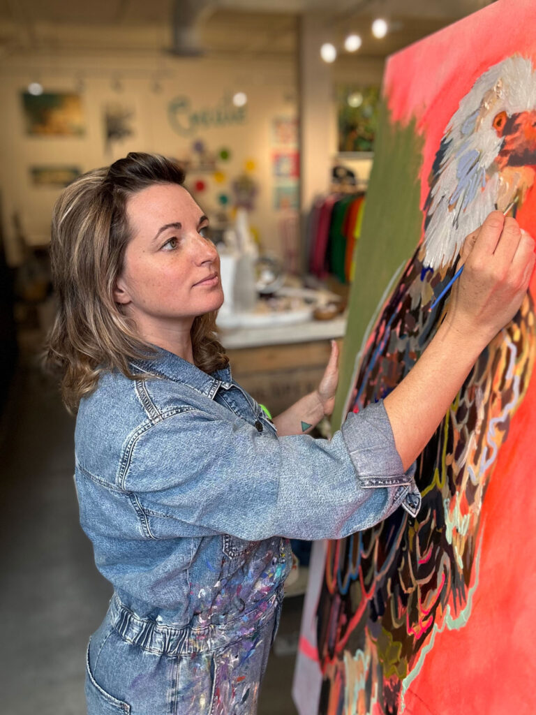 Andrea Mueller paints an eagle on a large canvas inside ART POP.