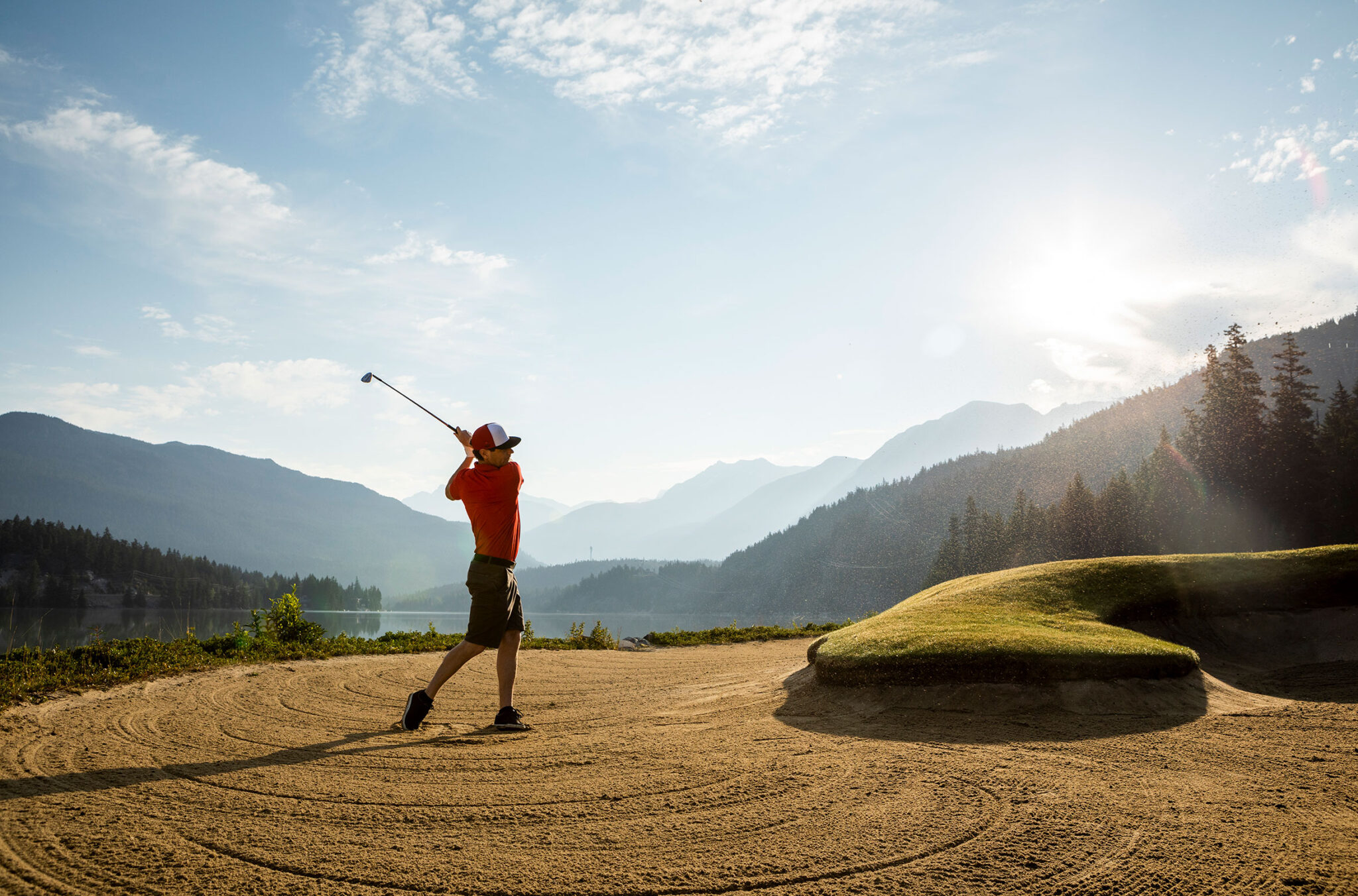 A golfer swings a club in the sand of one of the bunkers on the edges of Green Lake at Nicklaus North Golf Course in Whistler.