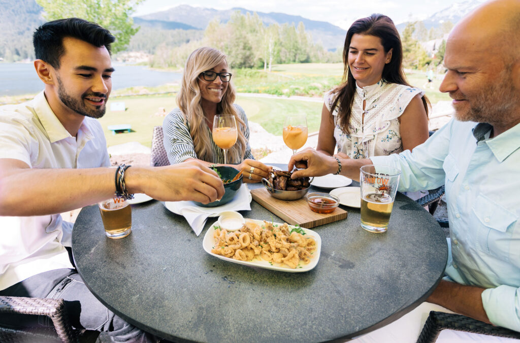 A group of friends enjoy apres at Table Nineteen at Nicklaus North Golf Course overlooking Green Lake in Whistler.