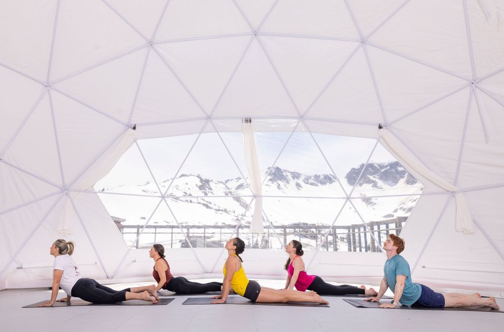 Five people practice yoga in a dome in the alpine in Whistler as part of the Nourish Whistler Wellness Series.