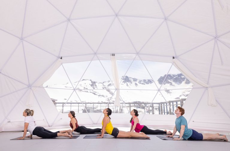 Five people practice yoga in a dome in the alpine in Whistler as part of the Nourish Whistler Wellness Series.