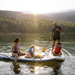 A family on two paddle boards explore Whistler's waterways in the summer sun.