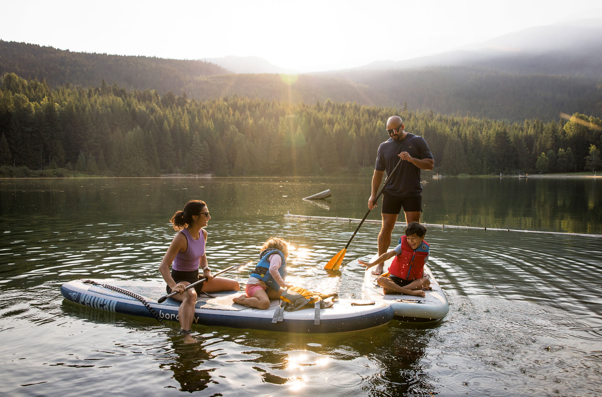 A family on two paddle boards explore Whistler's waterways in the summer sun.