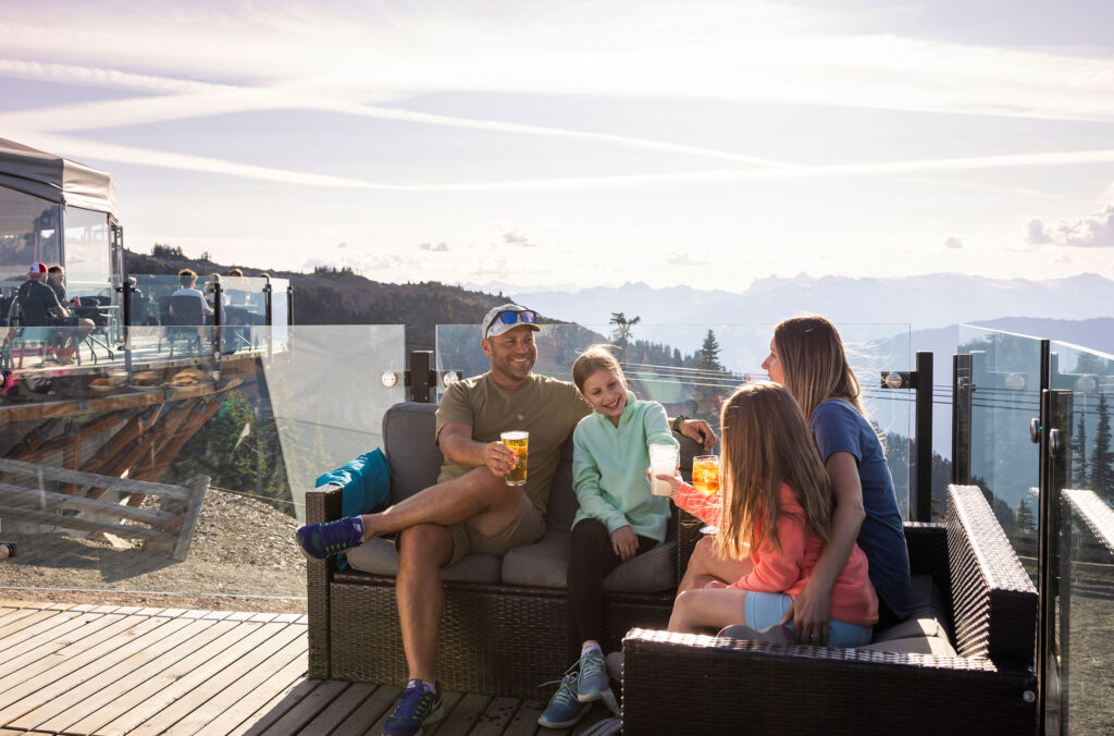 A family enjoys drinks on the sunny patio of the Roundhouse Lodge on Whistler Mountain.