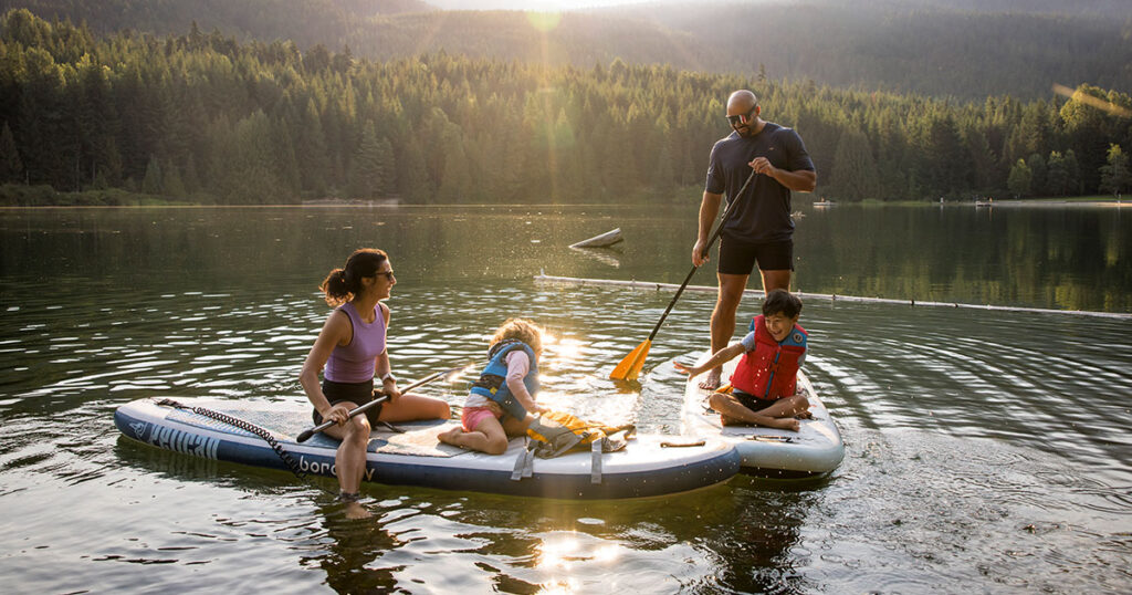 A family on two paddle boards explore Whistler's waterways in the summer sun.