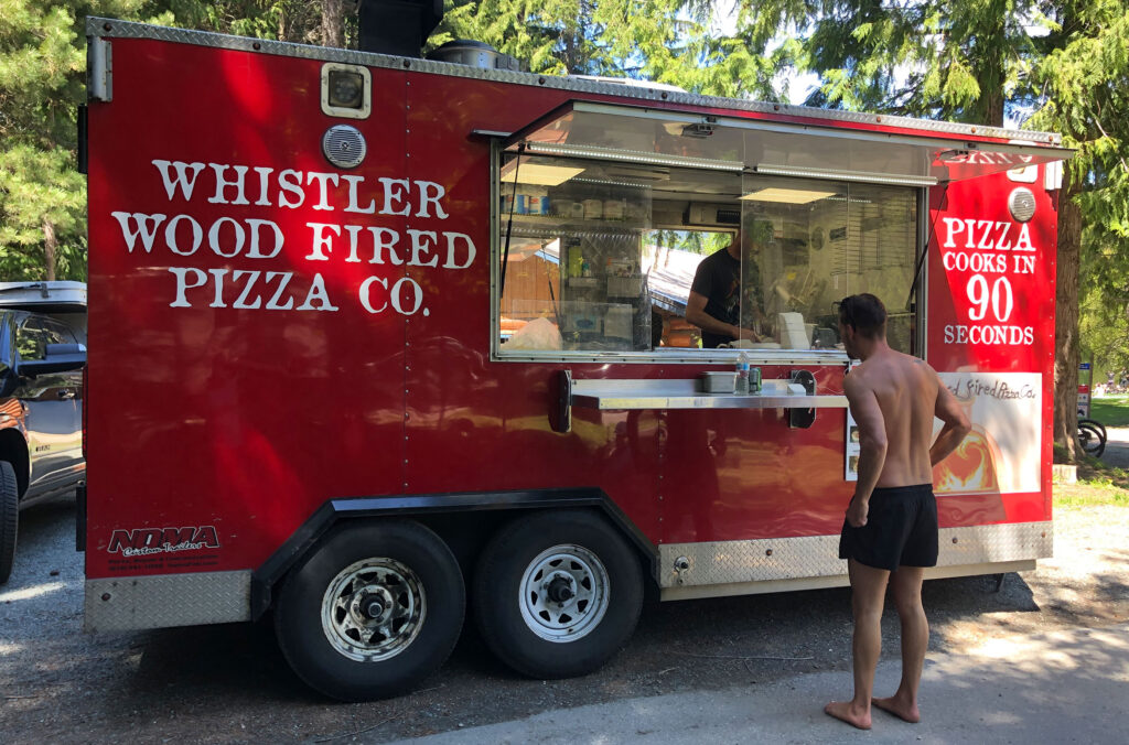 The vibrant red Whistler Wood Fired Pizza Co. food truck serves Whistler park-goers.