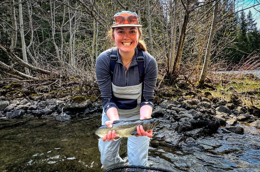 Hannah Hughes beams as she holds a trout in her hands on her trip out with Whistler Year-Round Fishing.