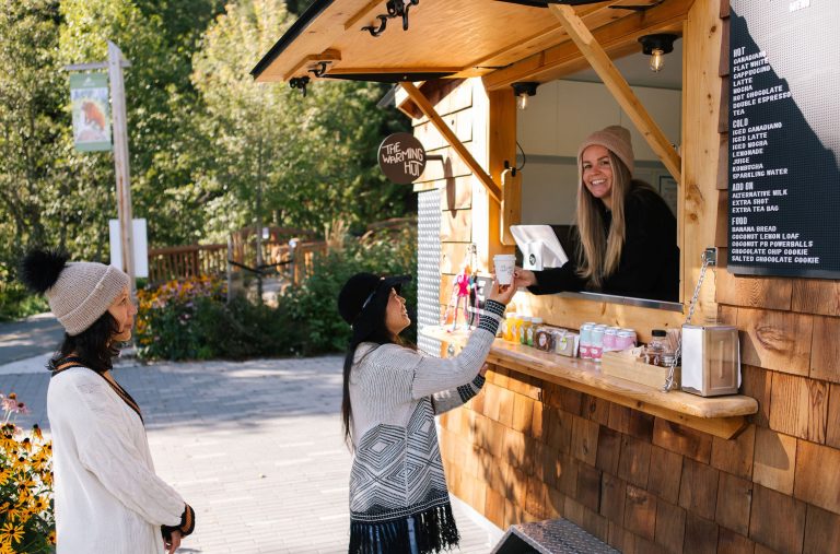 Two people get coffee from The Warming Hut food truck in Whistler's parks in the summertime.