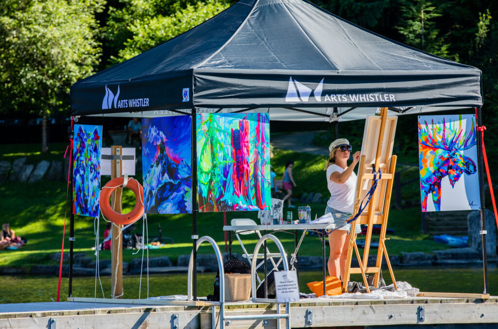A painter works away while floating on a lake dock in Whistler.