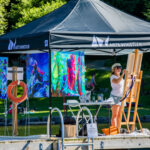 A painter works away while floating on a lake dock in Whistler.