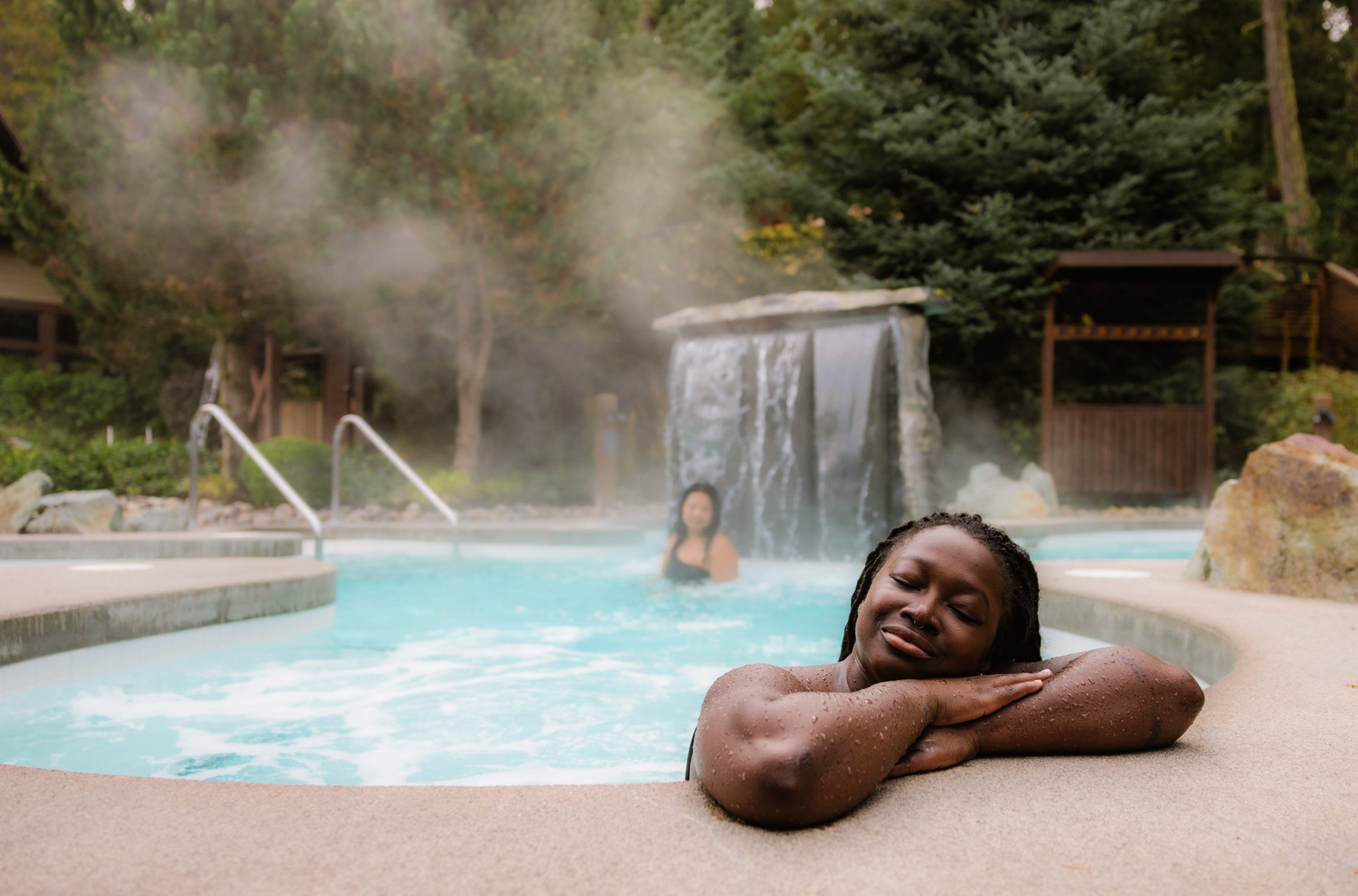 A person relaxes on the edge of a hot pool at the Scandinave Spa in Whistler.