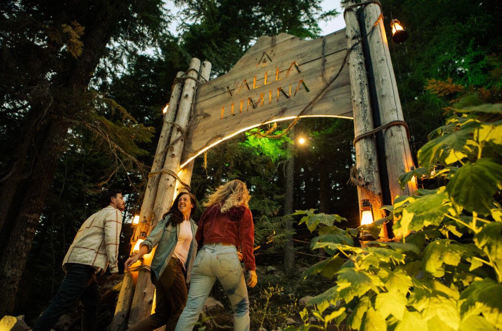Three friends head into the Vallea Lumina experience in the forests of Whistler.