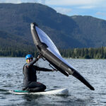Kate Heskett kneels on the board of a wing foil as she learns to control the foil.