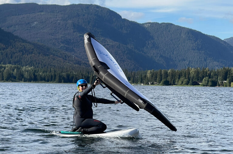 Kate Heskett kneels on the board of a wing foil as she learns to control the foil.