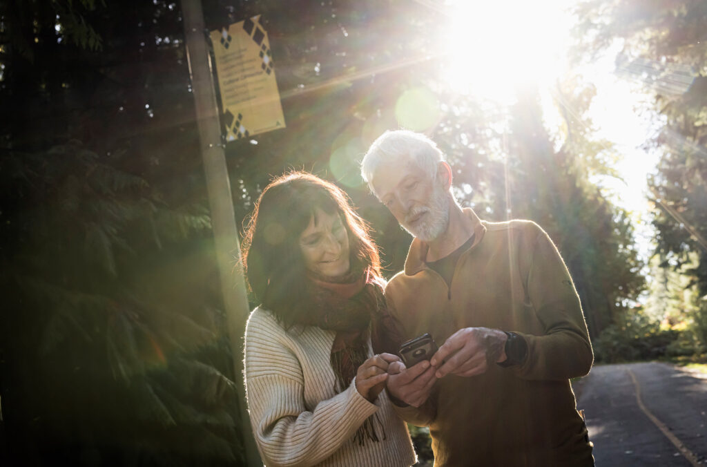A couple look at the Go Whistler Tours app on their phone as they explore Whistler in the fall.