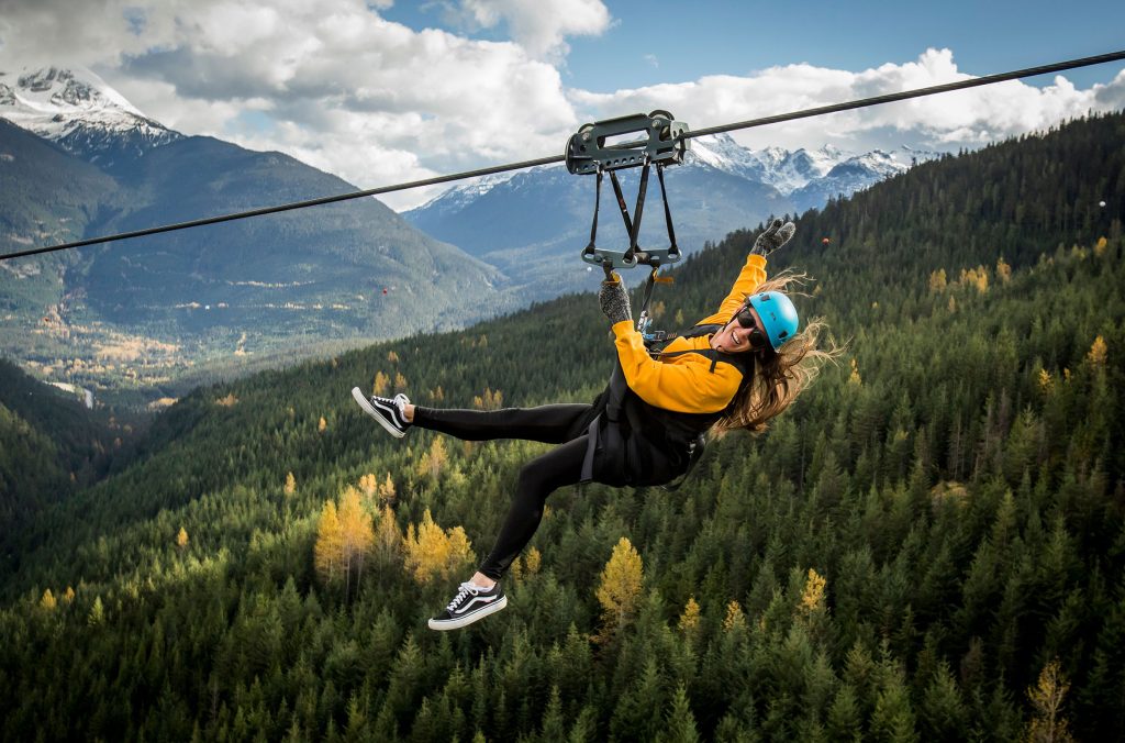 A person ziplines across the valley in Whistler in the fall.