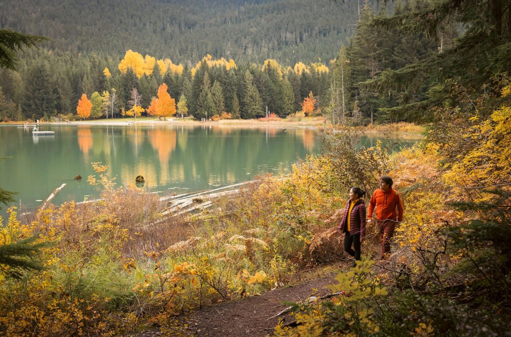 Two people explore Lost Lake Park in the fall colours.