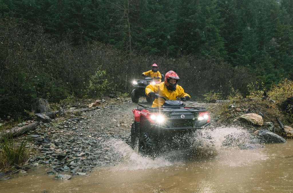 ATVs blast through a muddy puddle in Whistler's wilderness.